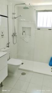 a white bathroom with a shower and a toilet at Aguazul - A pie de piscina y vistas al mar in Puerto del Carmen