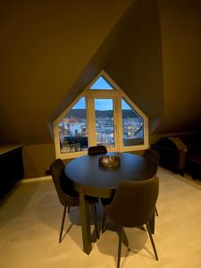 a table and chairs in a room with a large window at Penthouse with private balcony in the city centre of Bergen in Bergen