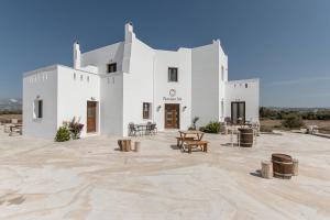 a white building with tables and benches in front of it at Naxian Air in Agios Georgios