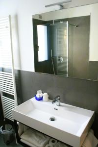 bagno con lavandino bianco e specchio di Hotel Cristallo a Lignano Sabbiadoro
