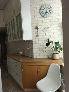 een keuken met een klok op een witte bakstenen muur bij Apartament w sercu Malborka in Malbork