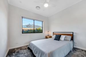 a white bedroom with a bed and a window at Velo Station in Porepunkah