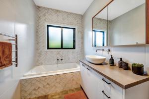 a bathroom with a sink and a tub and a mirror at Velo Station in Porepunkah +8 photos