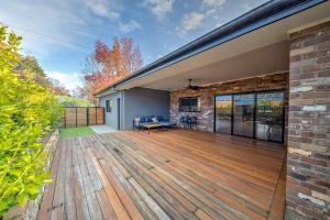 a large wooden deck with a brick wall at Velo Station in Porepunkah