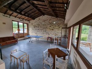 Habitación con mesas, sillas y pared de ladrillo. en Aldea Rural A Cortiña en Pepín