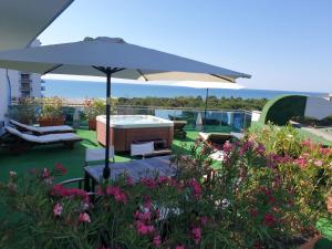 a patio with an umbrella and chairs and flowers at Hotel Cristallo in Lignano Sabbiadoro