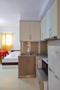 una cocina con armarios blancos y una cama en una habitación en Hotel Argjiro en Sarandë