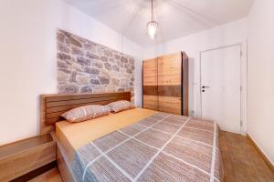 ein Schlafzimmer mit einem Bett und einer Steinmauer in der Unterkunft Happy Home Apartments in Kotor