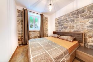 ein Schlafzimmer mit einer Steinmauer und einem Bett in der Unterkunft Happy Home Apartments in Kotor