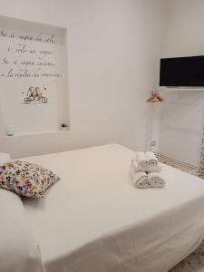 uma cama branca com toalhas e uma placa na parede em I VACANZIERI em Avola
