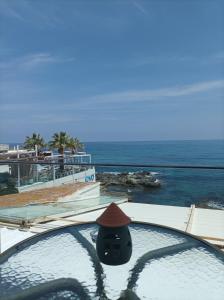 una persona con un cappello seduta in una piscina con vista sull'oceano di Beachfront apartment a Rethymno