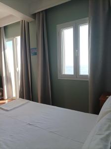 una camera con un letto bianco e due finestre di Beachfront apartment a Rethymno