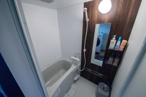 ein kleines Bad mit einer Badewanne und einem Waschbecken in der Unterkunft Landmark Annex in Furano