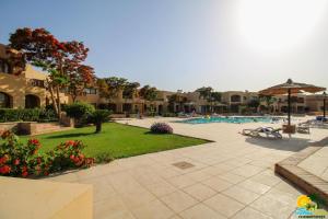 an outdoor swimming pool with an umbrella and a yard at Bellevue The View in Hurghada