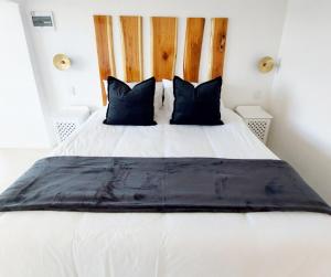 a bedroom with a large white bed with black pillows at Number 3 in Plettenberg Bay
