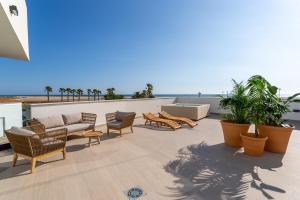 a patio with chairs and a couch on a roof at Hotel Apartamentos Hamus in Conil de la Frontera