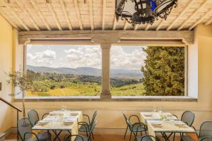 ein Zimmer mit Tischen und Stühlen und einem großen Fenster in der Unterkunft Agriturismo Fattoria Di Maiano in Fiesole