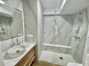 y baño blanco con lavabo y ducha. en Apartamento TDC12 en Gijón