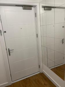 a white closet with a door and a shower at Lux One Bedroom Apartment in Barking