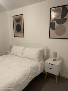 een slaapkamer met een wit bed en een nachtkastje met een lamp bij Lux One Bedroom Apartment in Barking