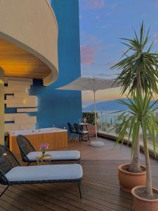 a patio with two palm trees and chairs on a deck at Priam Hotel Luxury Resort in Vlorë