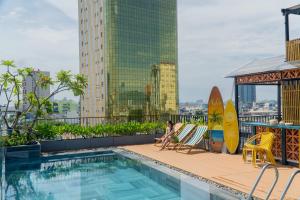 a person sitting in a chair next to a swimming pool at Seahorse Signature Danang Hotel by Haviland in Danang