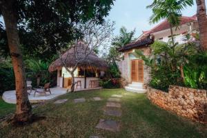 a garden with a house with a thatch roof at Bodhi Bingin in Uluwatu
