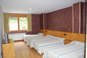 three beds lined up in a room at Hostal Los Valles in Bielsa