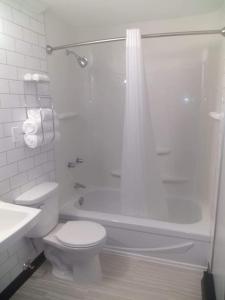 y baño blanco con aseo y ducha. en Acadian Hotel en Stephenville