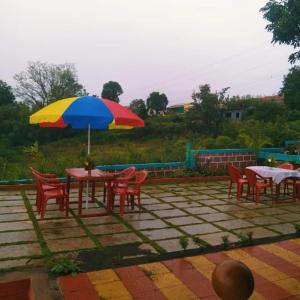 a table and chairs with a colorful umbrella at KAASH PATHAR DREAM HOUSE in Satara