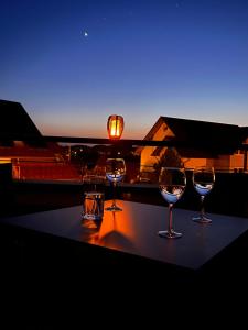 ヴァンゲン・イム・アルゴイにあるApartment mit Dachterrasse & Saunaの夕日を眺めながらテーブルに座るワイングラス4杯