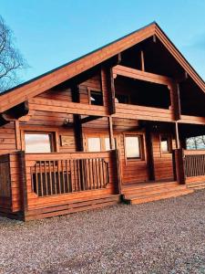 a large wooden cabin with a large balcony at Pentland Lodge in Gorebridge