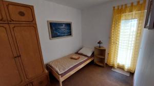 ein kleines Schlafzimmer mit einem kleinen Bett und einem Fenster in der Unterkunft Apartman SABADIN in Njivice