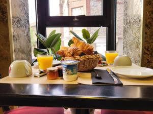 a table with a basket of bread and glasses of orange juice at Chambres d'Hôtes La petite Salamandre in Étretat