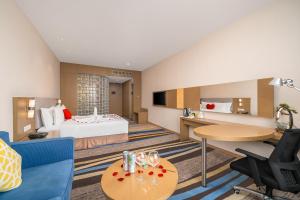 広州市にあるVyluk Hotel Guangzhou Baiyun International Airportのベッド、テーブル、椅子が備わるホテルルームです。