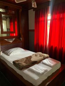 a bed with red curtains and a blanket on it at Hotel Karisma II in São Bernardo do Campo