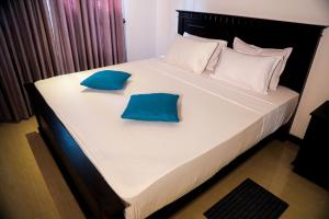 a large bed with two blue pillows on it at Villana Villa Bentota in Bentota