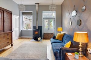 ein Wohnzimmer mit einem blauen Sofa und einem Holzofen in der Unterkunft Westwood Cottage in Dundee