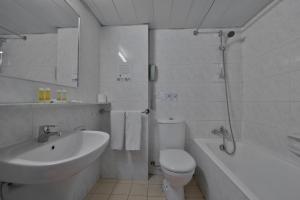a white bathroom with a sink and a toilet and a tub at Odysseia Hotel Kapetanios in Limassol