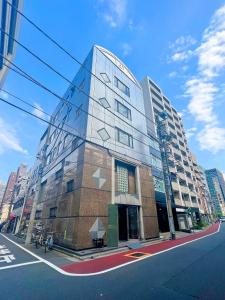 a tall glass building on a city street at Akihabara Nakagawa Inn in Tokyo