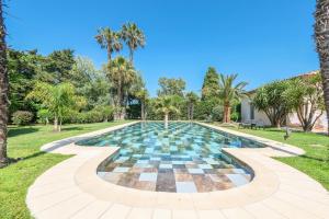 a pool in a park with palm trees at Villa Alizée B&B in Saint-Tropez