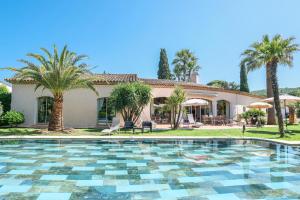 a swimming pool in front of a house with palm trees at Villa Alizée B&B in Saint-Tropez