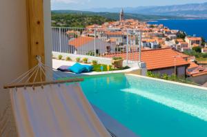 a pool with a hammock and a view of a city at Villa Bella Vista in Vrbnik