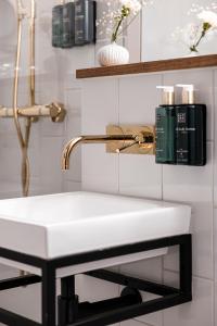 a bathroom with a white sink and a gold faucet at Clarion Hotel Amaranten in Stockholm