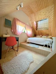 a bedroom with a bed and a desk and a red chair at Amazing little house on an island with garden in Riga