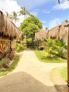 a path leading to a house with a straw roof at Siargao Tropic Hostel in General Luna