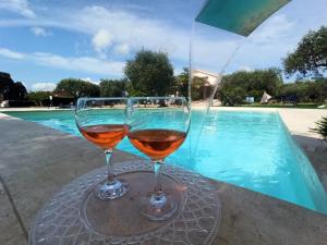 dos copas de vino sentadas en una mesa cerca de una piscina en Villa Marianna, en Alghero