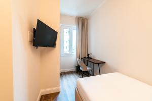 a room with a bed and a desk with a television at Hotel del Conte in Laveno-Mombello