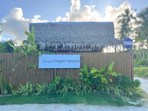a sign for a tropic house in front of a fence at Siargao Tropic Hostel in General Luna