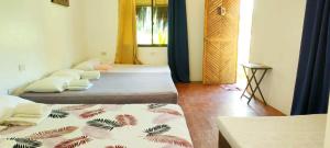 a room with three beds and a window at Siargao Tropic Hostel in General Luna